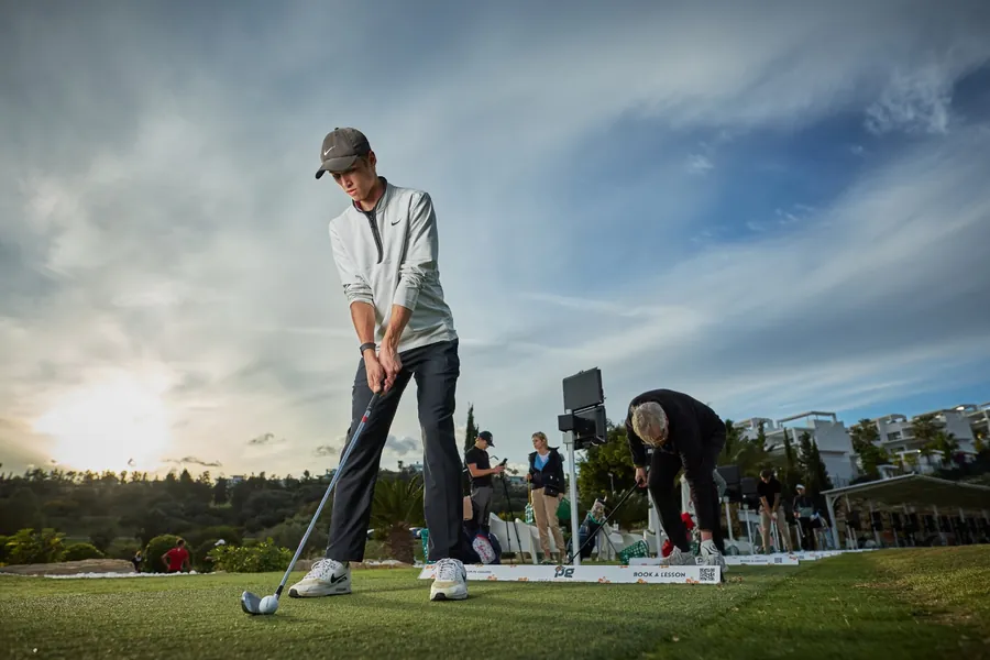 PG coach guiding a golfer through their swing on the range