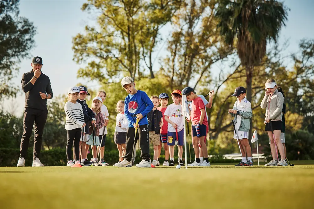 PG coach greeting junior golfers on the practice green